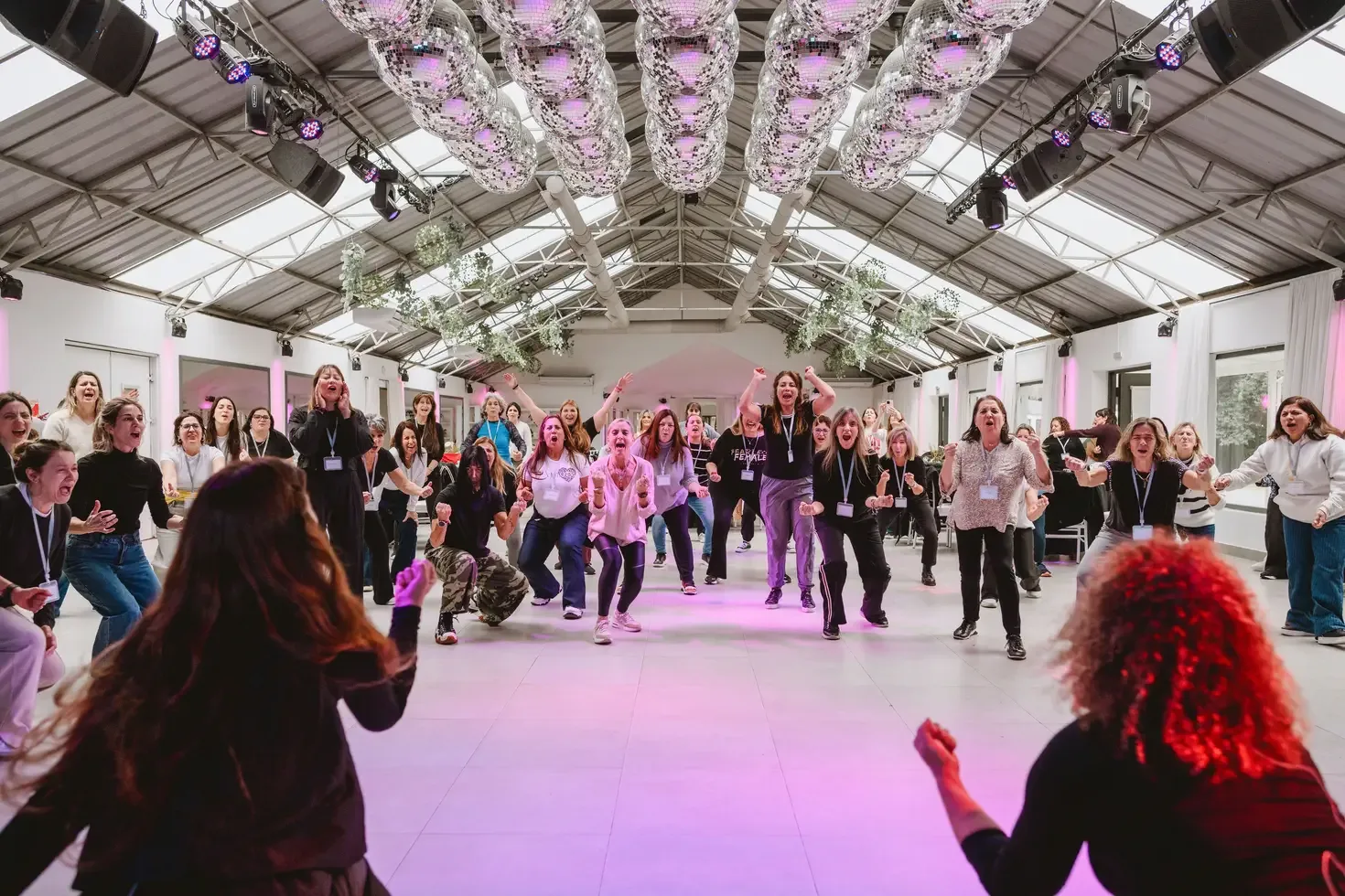 Un grupo grande de mujeres de pie en una jornada de Human Lab, con los brazos en alto y gesto de celebración.